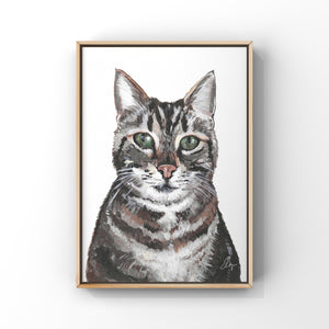 Framed painting of a cat portrait. The cat is a tabby with bright green eyes.
